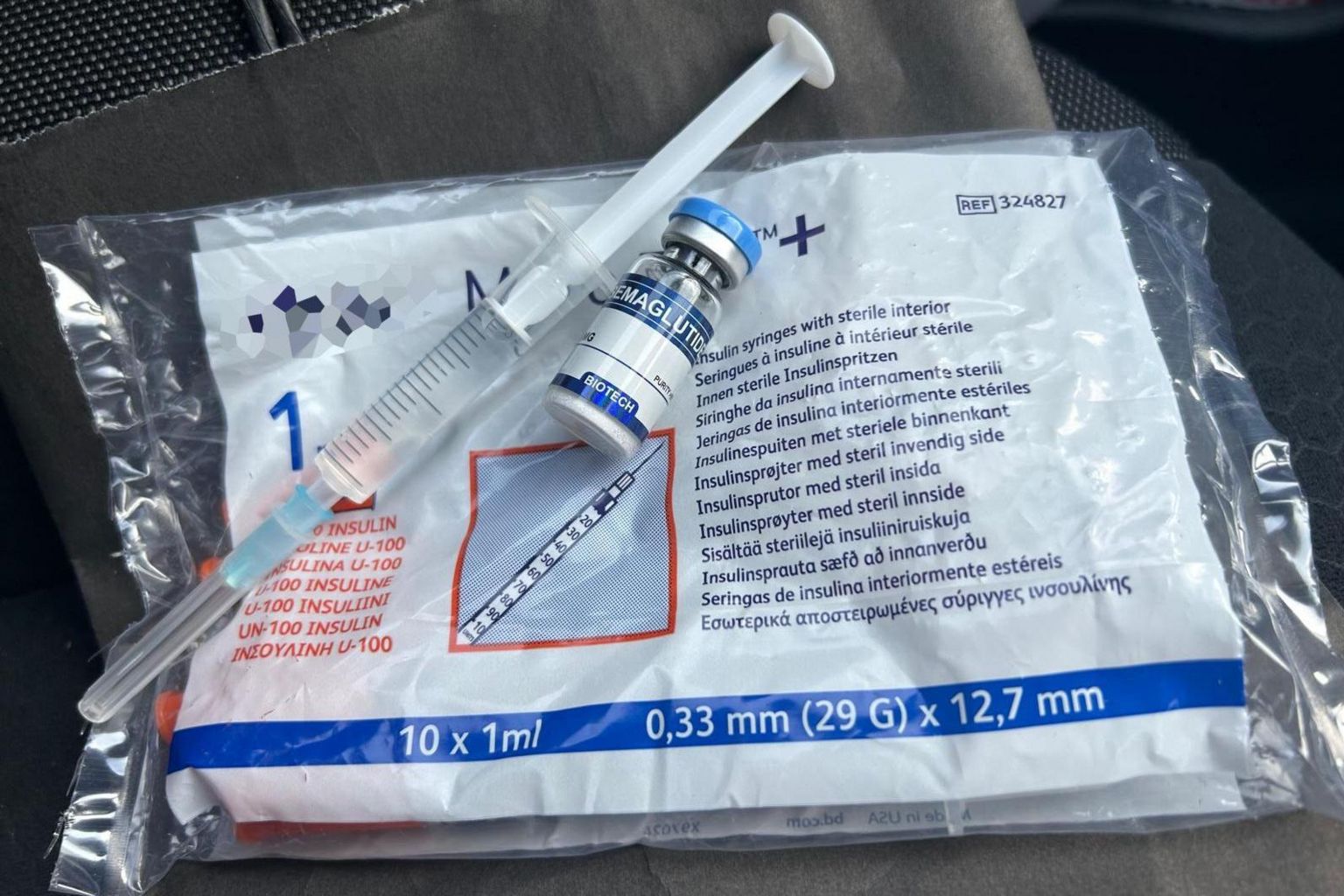 A syringe filled with liquid, vial marked "semaglutide" and bag of insulin syringes