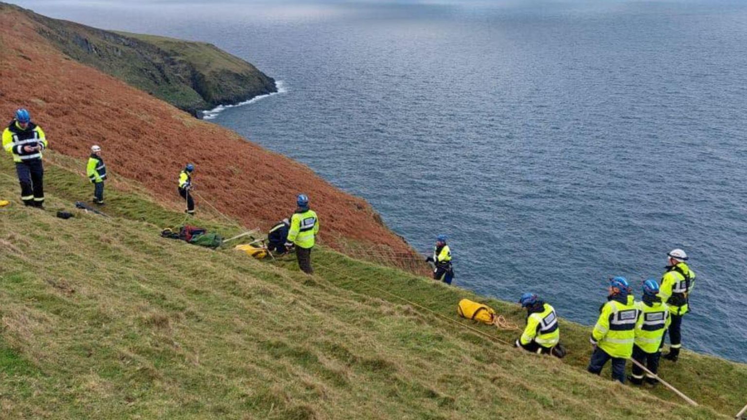 A coastguard team organising a rope rescue on the cliff edge