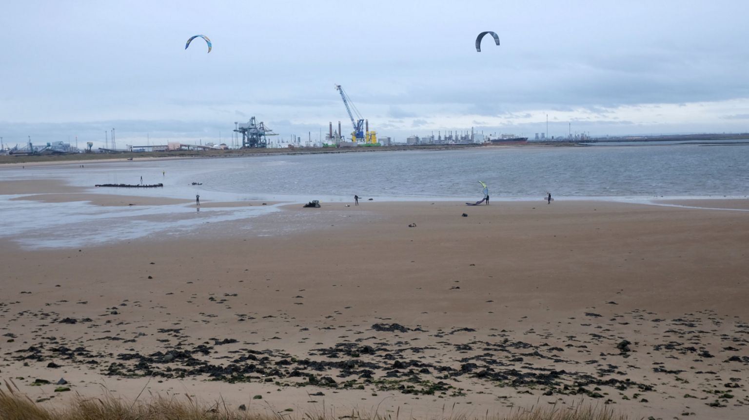 A sandy beach with cranes in the background