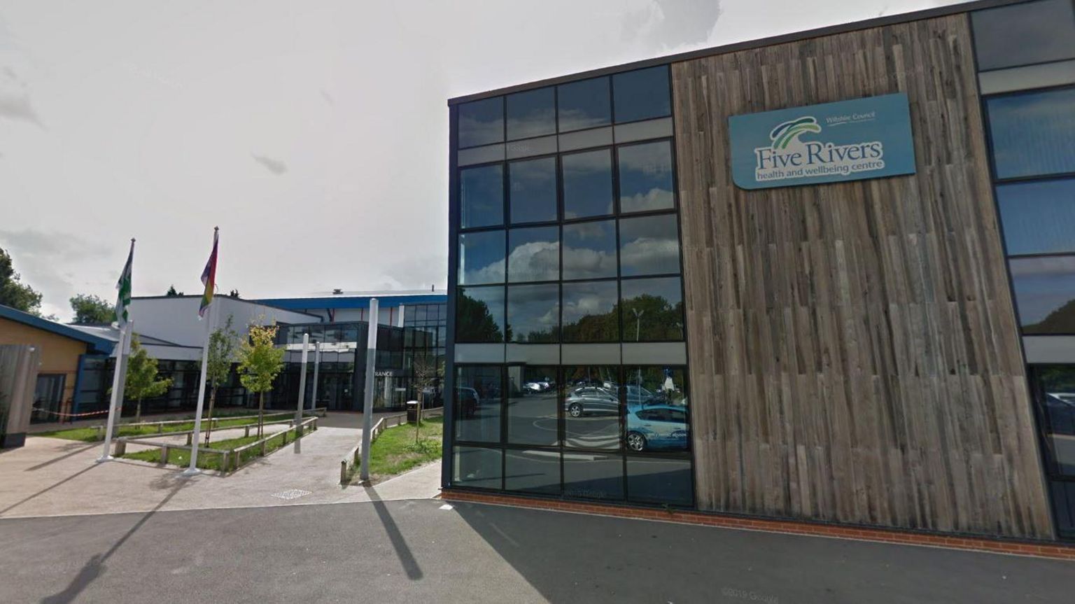 The entrance and side of Five Rivers leisure centre in Salisbury, which has dark grey wood panelling on the side.