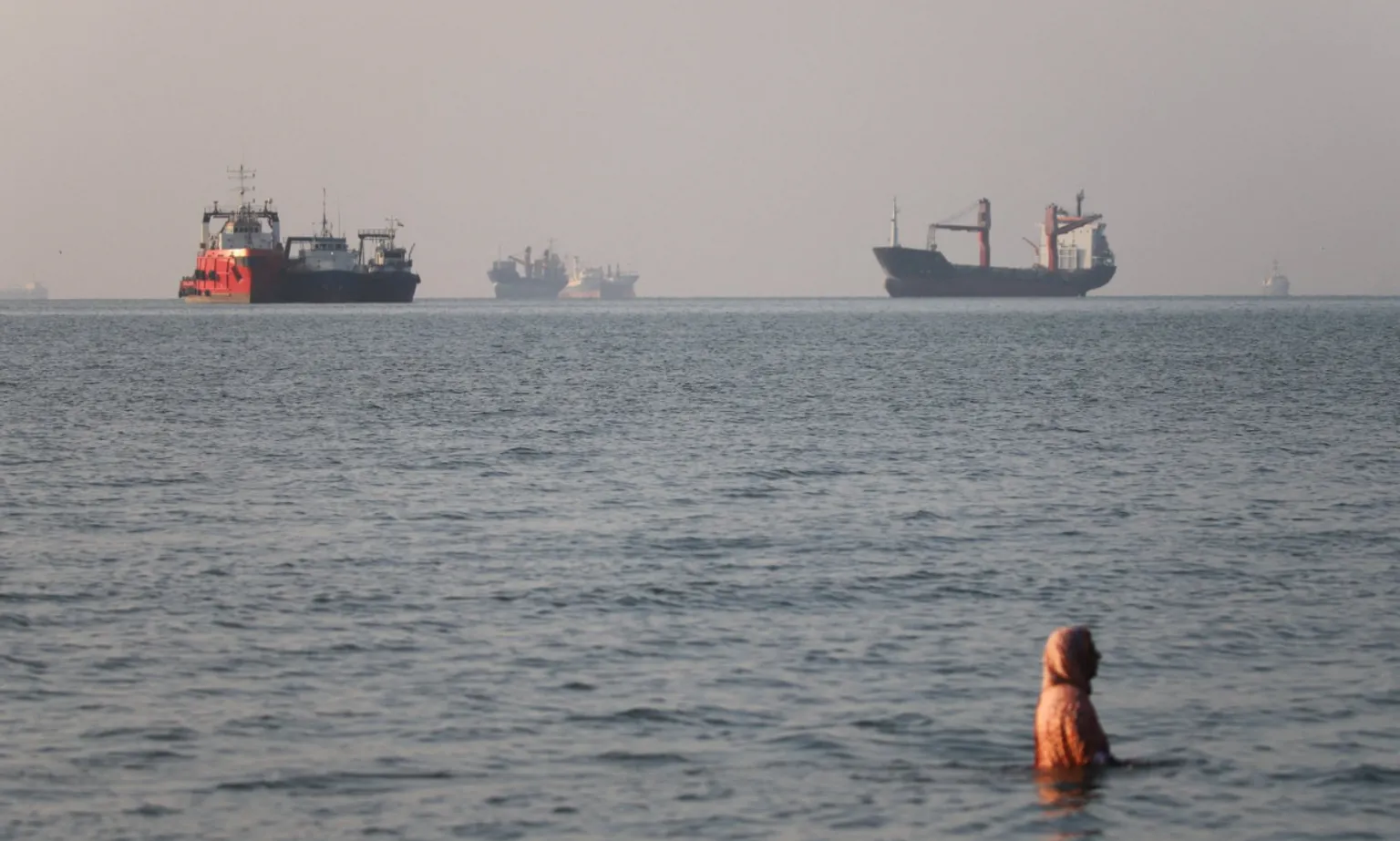 Reuters A woman in the water with a number of large vessels in the distance