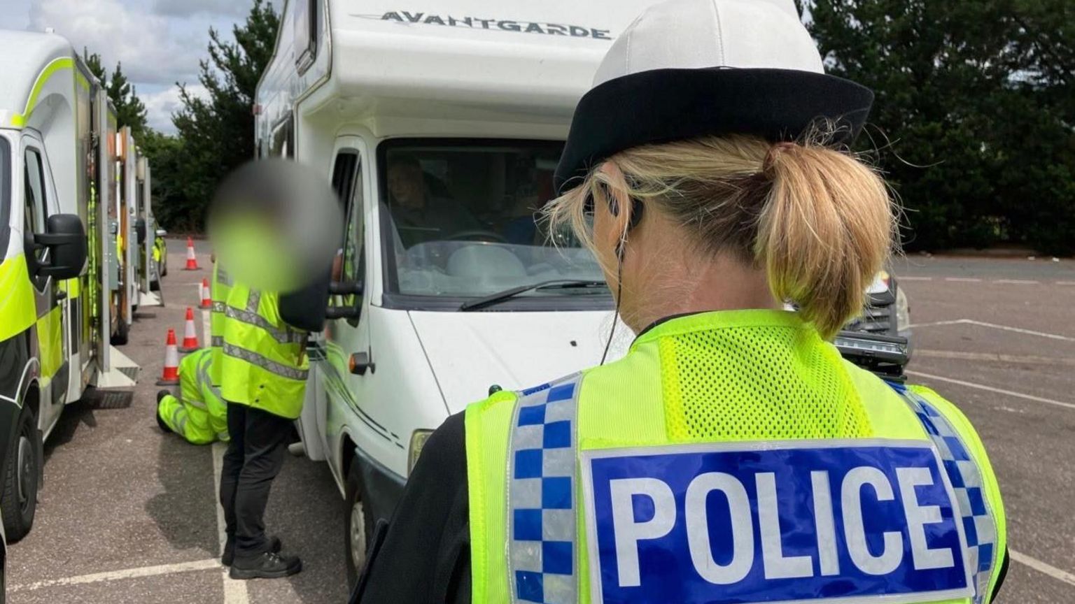 A female police officer in a high-vis jacket standing in front of a motorhome