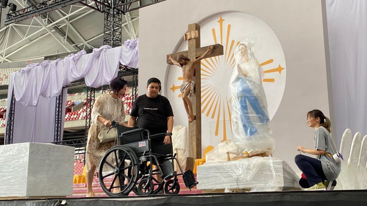 A volunteer pushes a wheelchair during a rehearsal for the Papal mass in Singapore.