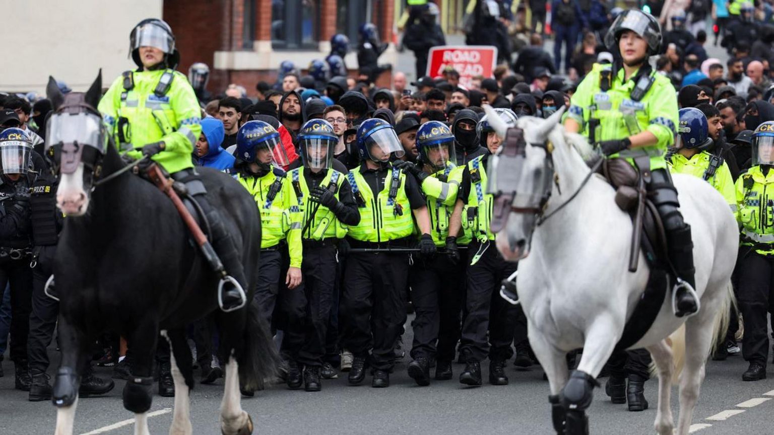 Mounted police officers and those in riot gear block rival protesters during an anti-immigration protest in Bolton.