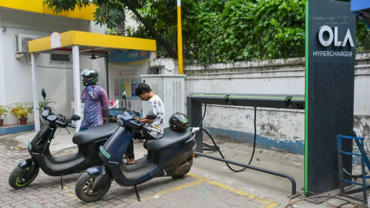 NurPhoto via Getty Images People are seen charging their electric scooters at An OLA electric vehicle hyper charging station in Kolkata , India.