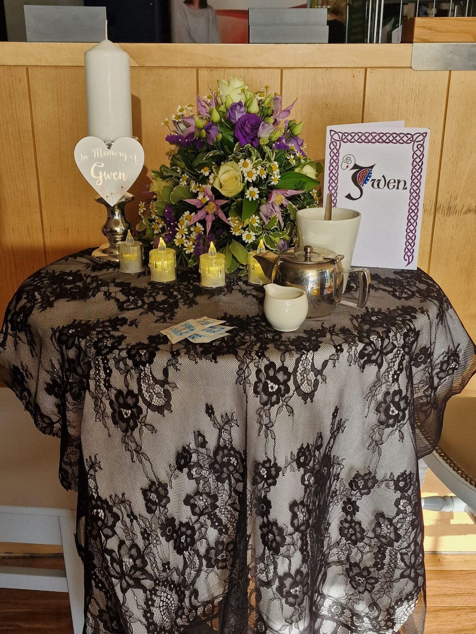 A table laid with flowers, candles, cards and a pot of tea, which was done on the day of Gwendoline Wain's funeral