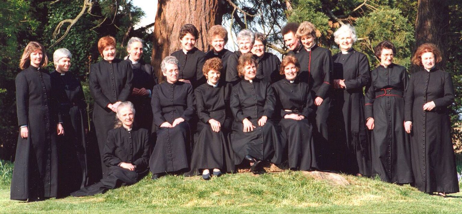 Eighteen women who had been ordained as priests feature as a group stood in front of two large trees
