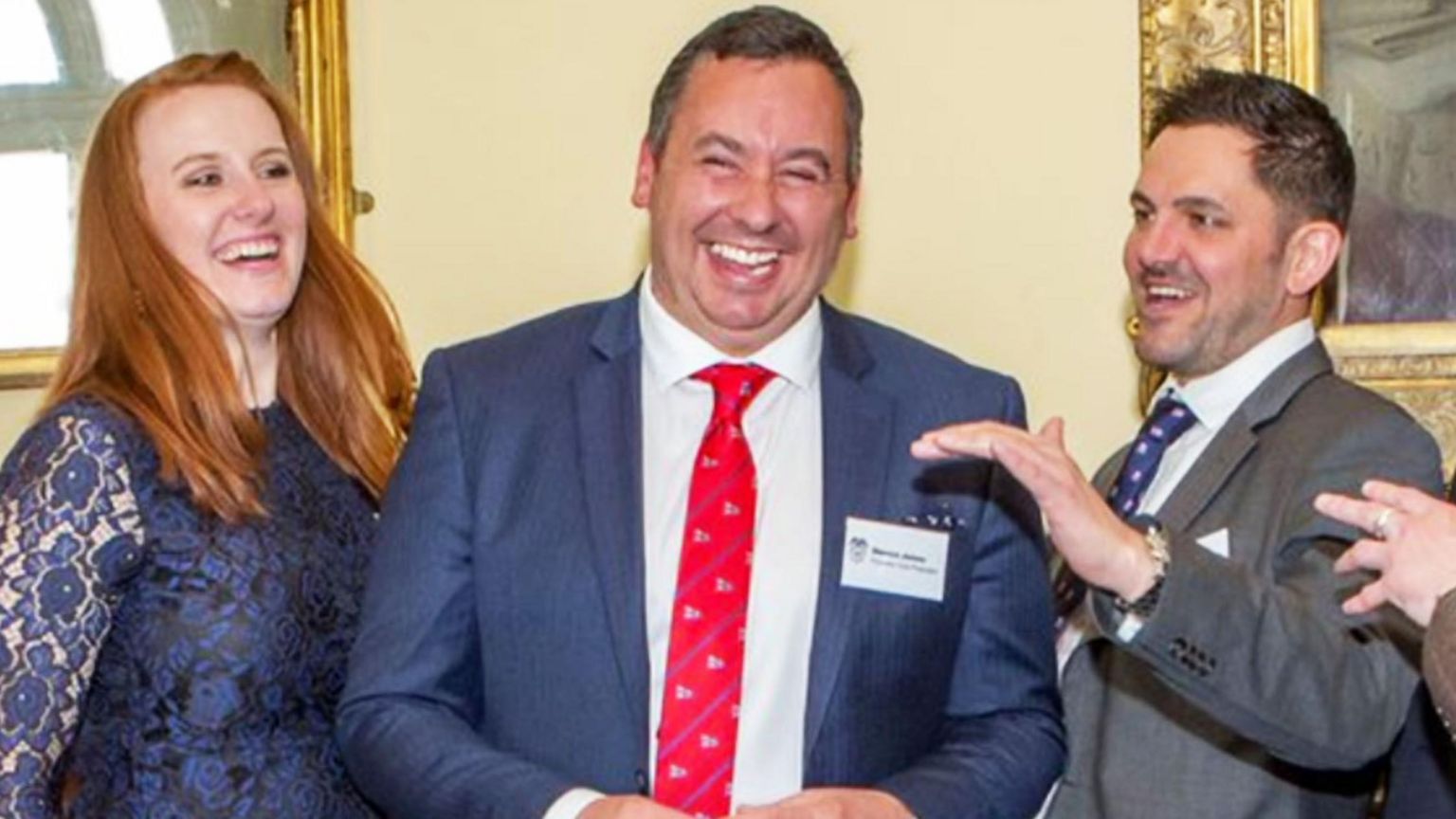 Steven Jones, in a blue suit, white shirt and red tie, with two campaigners, one woman with ginger hair and a blue lace dress and one man in a grey suit with a white shirt and blue tie