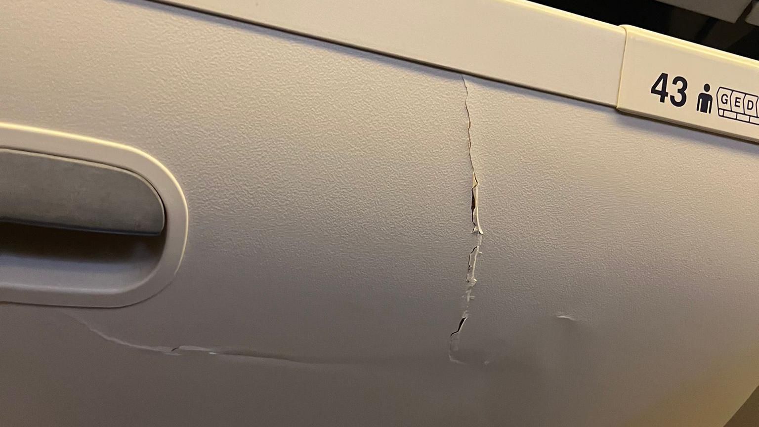 An overhead compartment cracked and visibly damaged