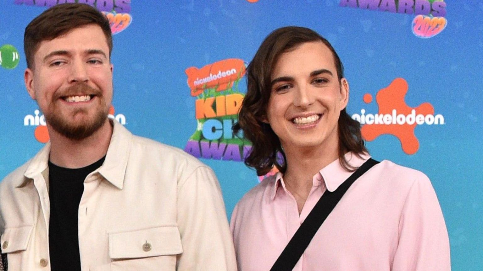 MrBeast pictured with Ava Kris Tyson at the Nickelodeon Kids Choice Awards. MrBeast has short brown hair and a short beard and wears a white overshirt over black T-shirt. Ava has shoulder-length brown hair parted to the side and wears a pink shirt. 