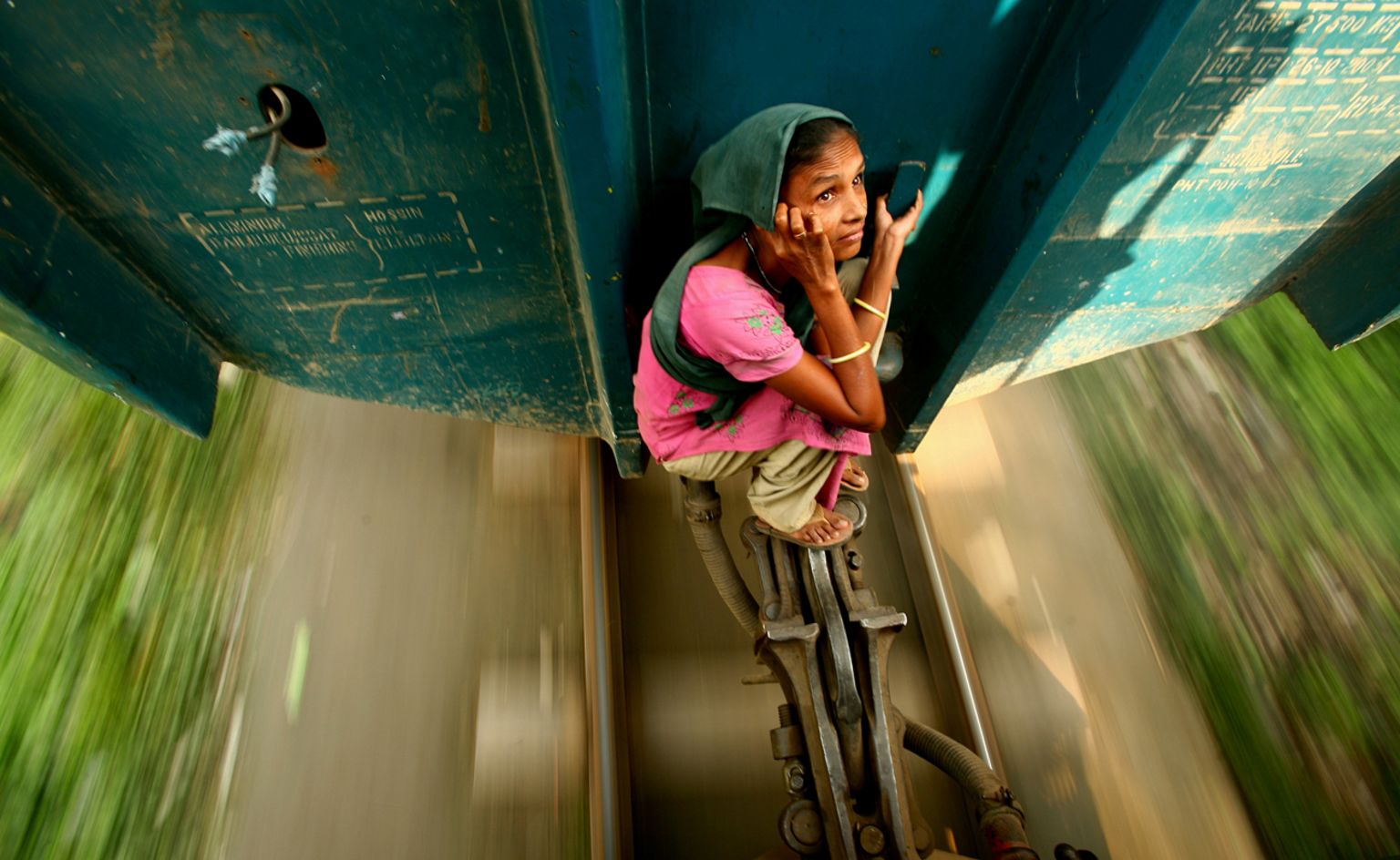 A woman travelling on the locking system of a carriage. Dhaka, Bangladesh