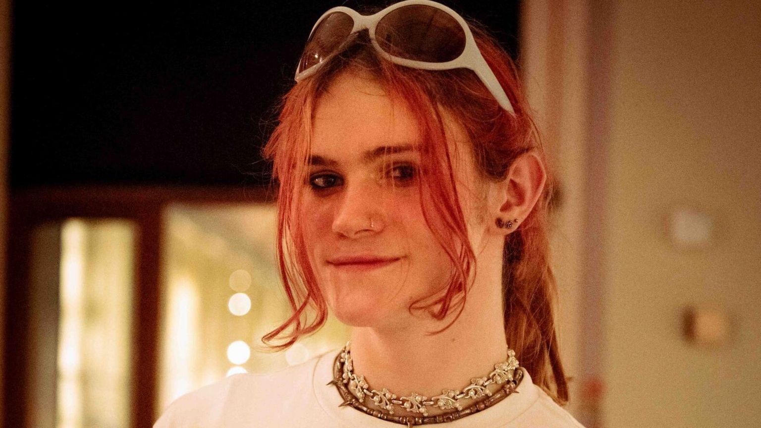 Artist Skye Baker smiles at the camera, with long pink hair and white-rimmed sunglasses on the top of her head