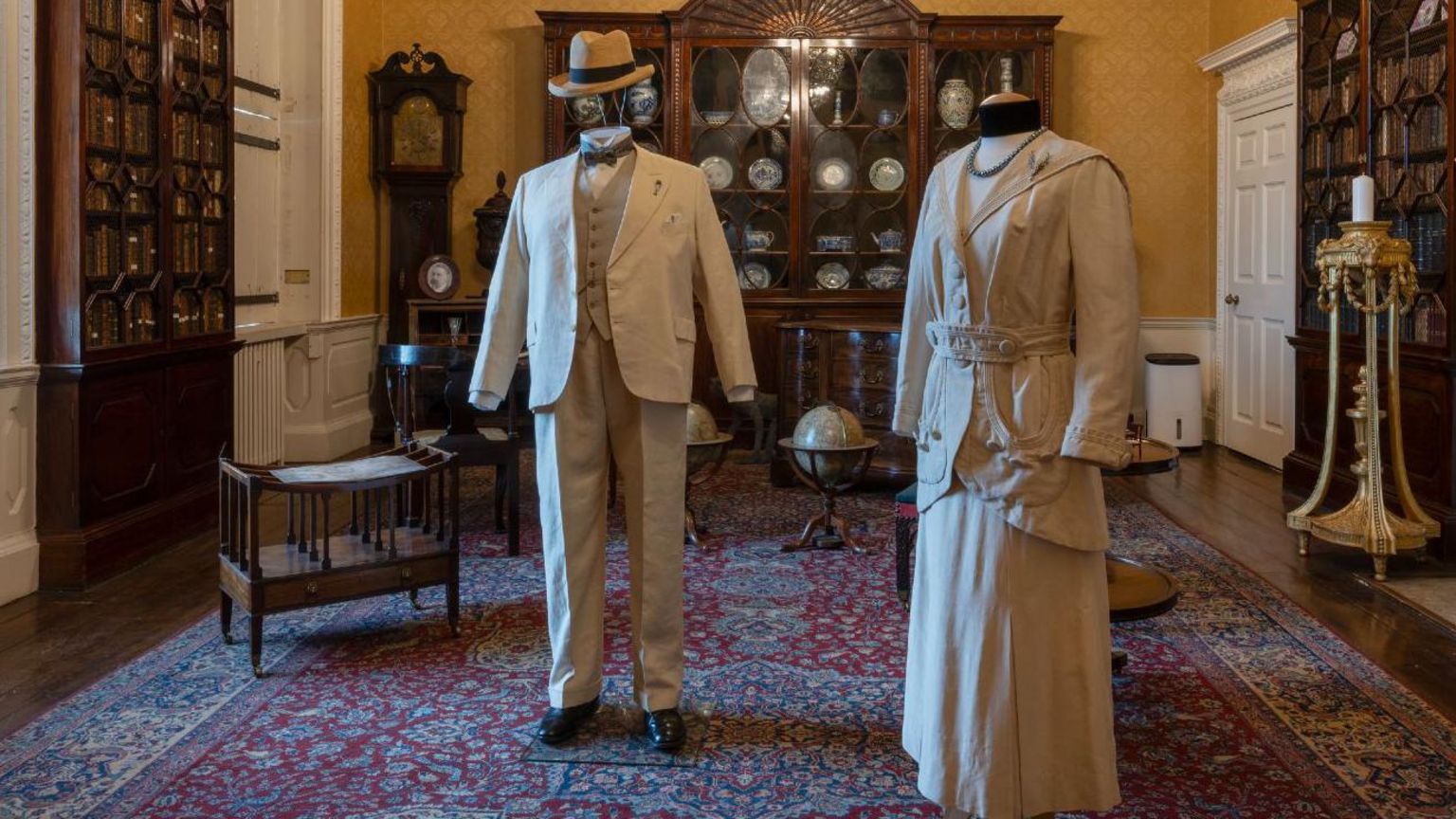A man's linen suit with straw Panama hat and a woman's cream linen and silk skirt and jacket - both in a 1930s style