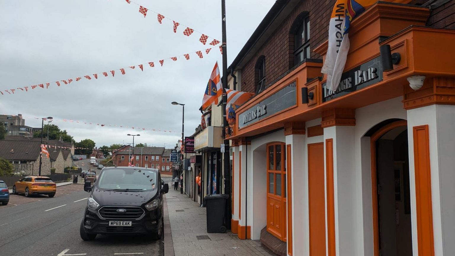 A pub painted orange and white and with orange and white bunding over the road that it is on