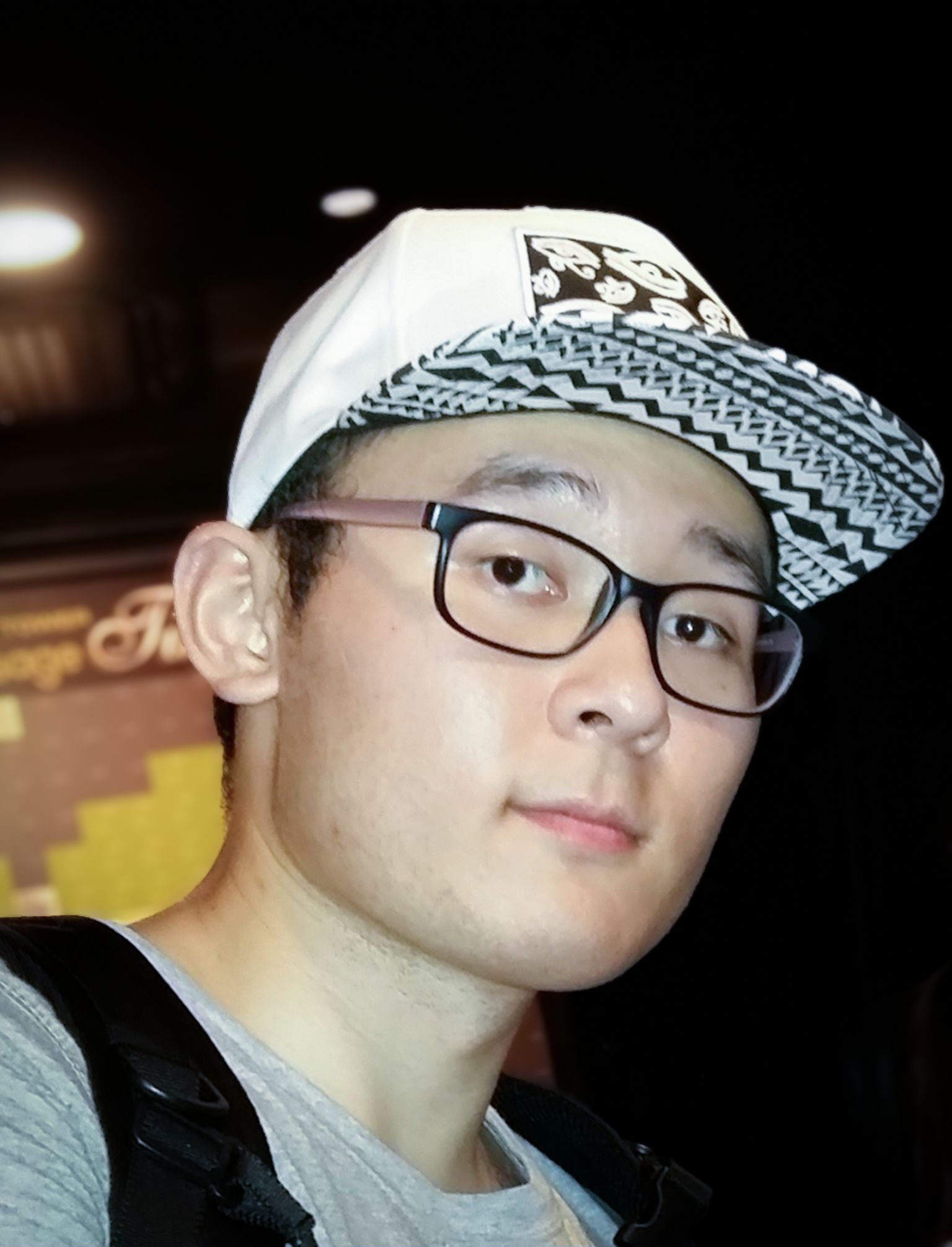 一位戴着黑白相间帽子和眼镜的年轻韩国男子看着镜头。