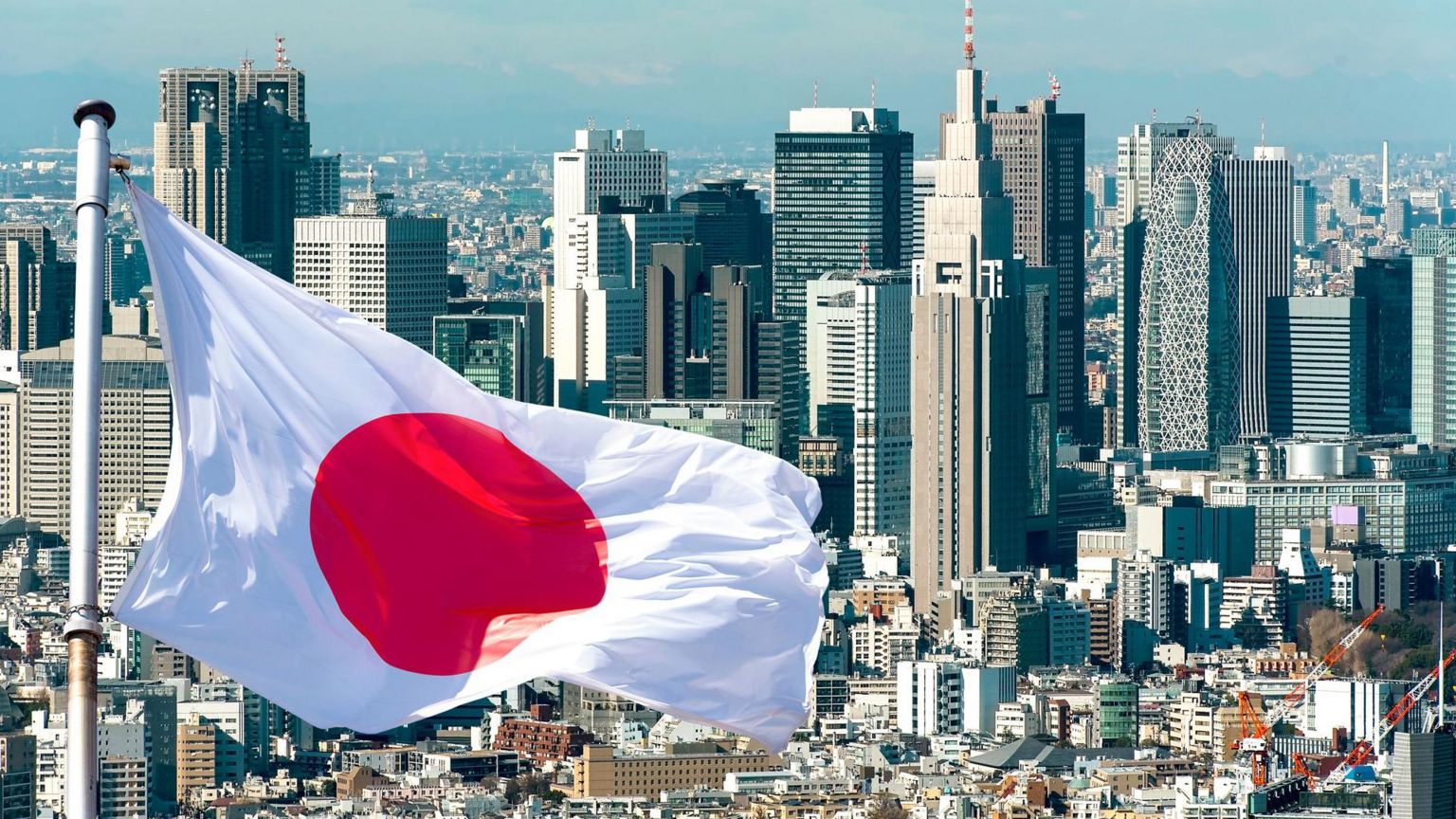 一面日本国旗在东京天际线前飘扬