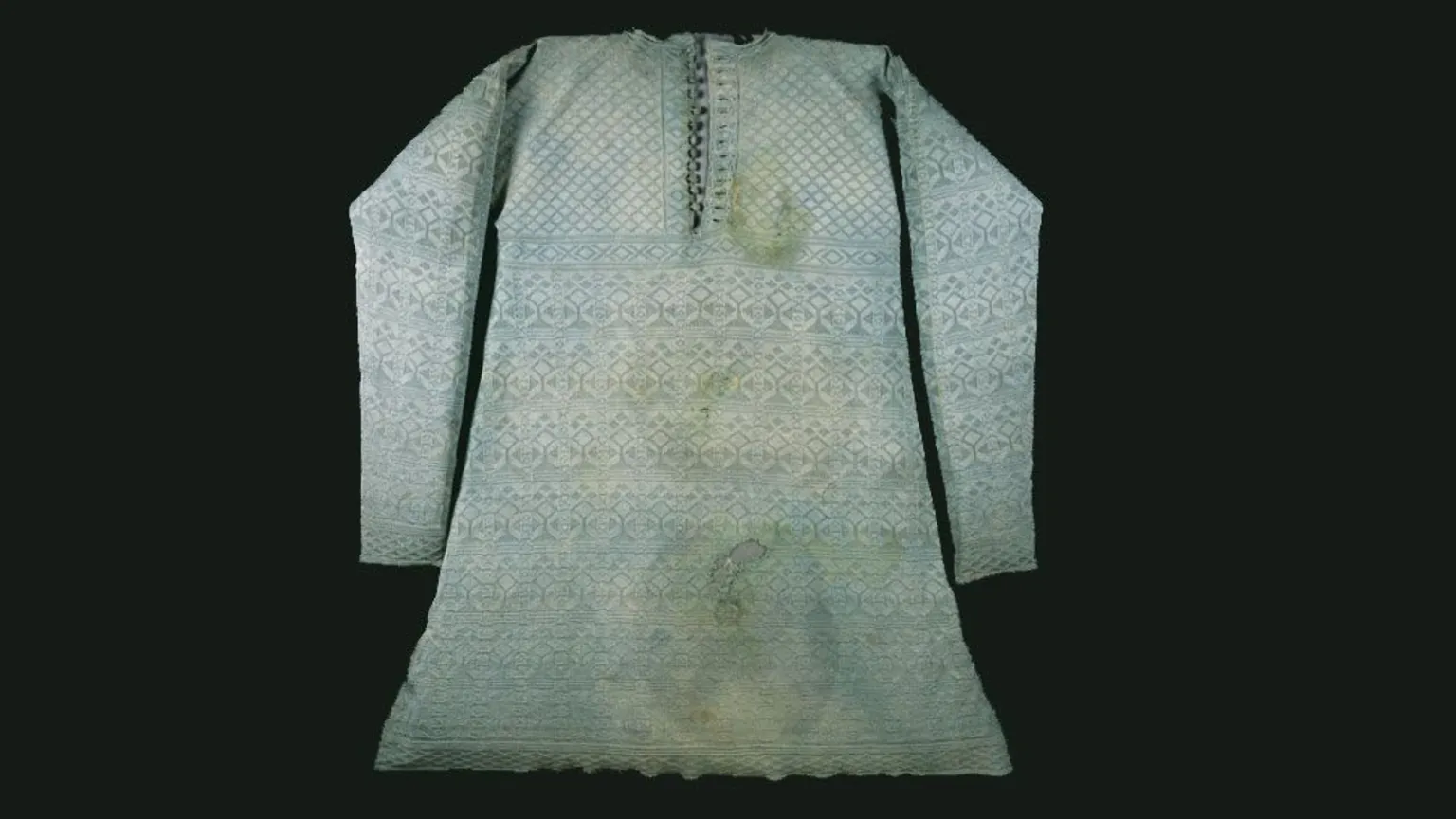 London Museum A light blue embroidered silk vest with stains on it against a black background