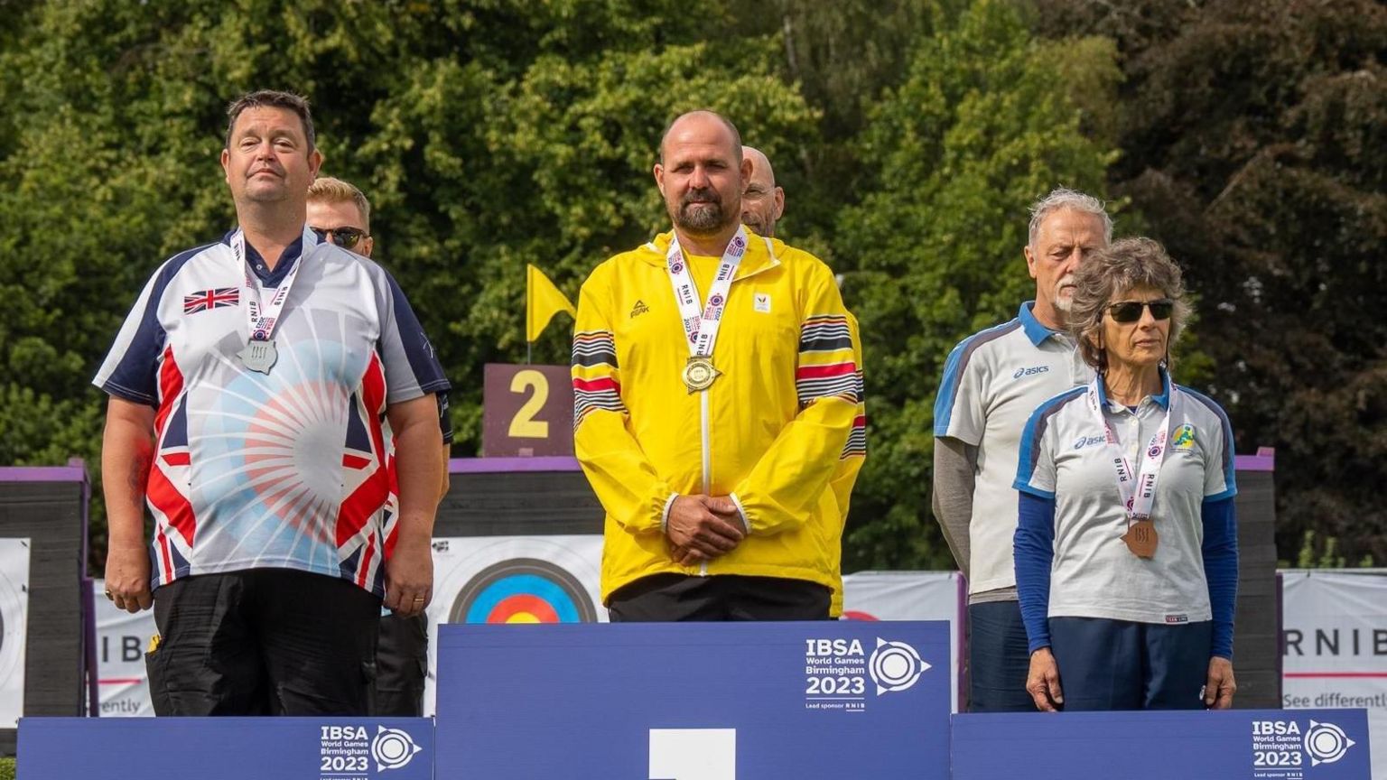 Clive Jones stands on the 2nd place podium in team GB clothing 
