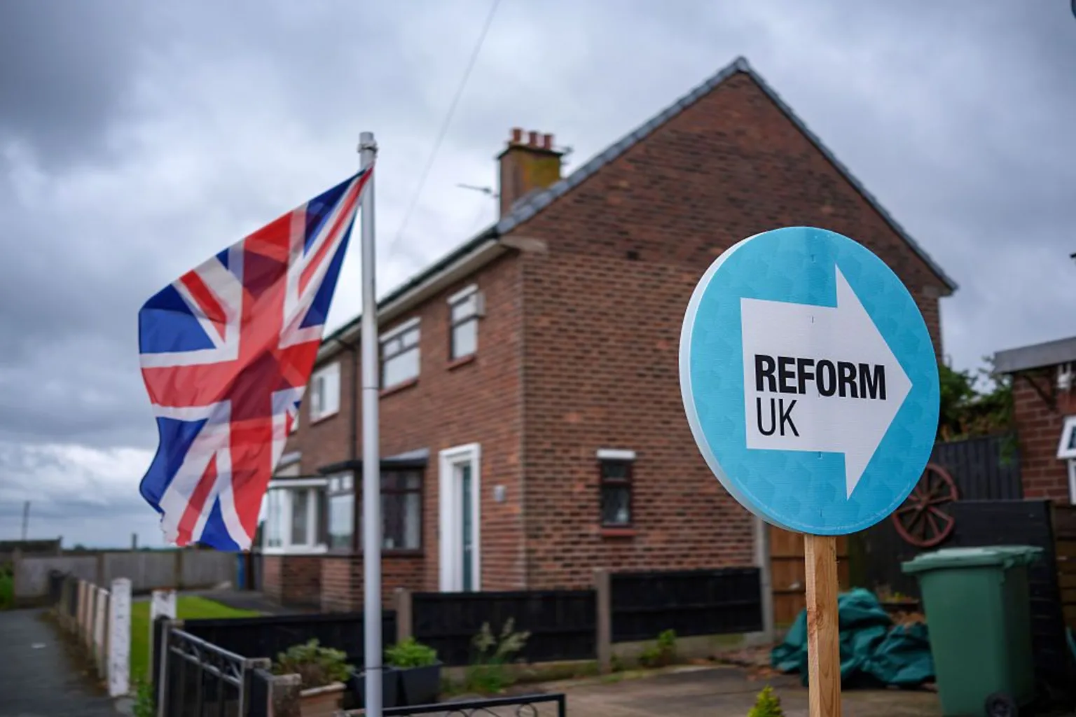 Getty Images A light blue Reform UK placard next to a Union Jack outside a house.
