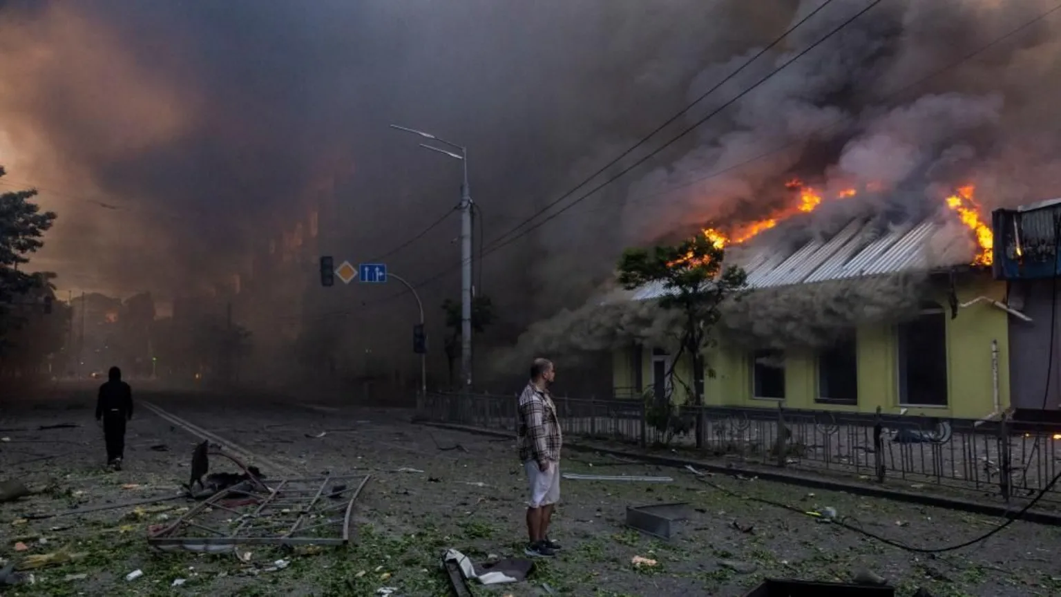Reuters A man looks at a burning building set ablaze during an overnight Russian missile and drone strike