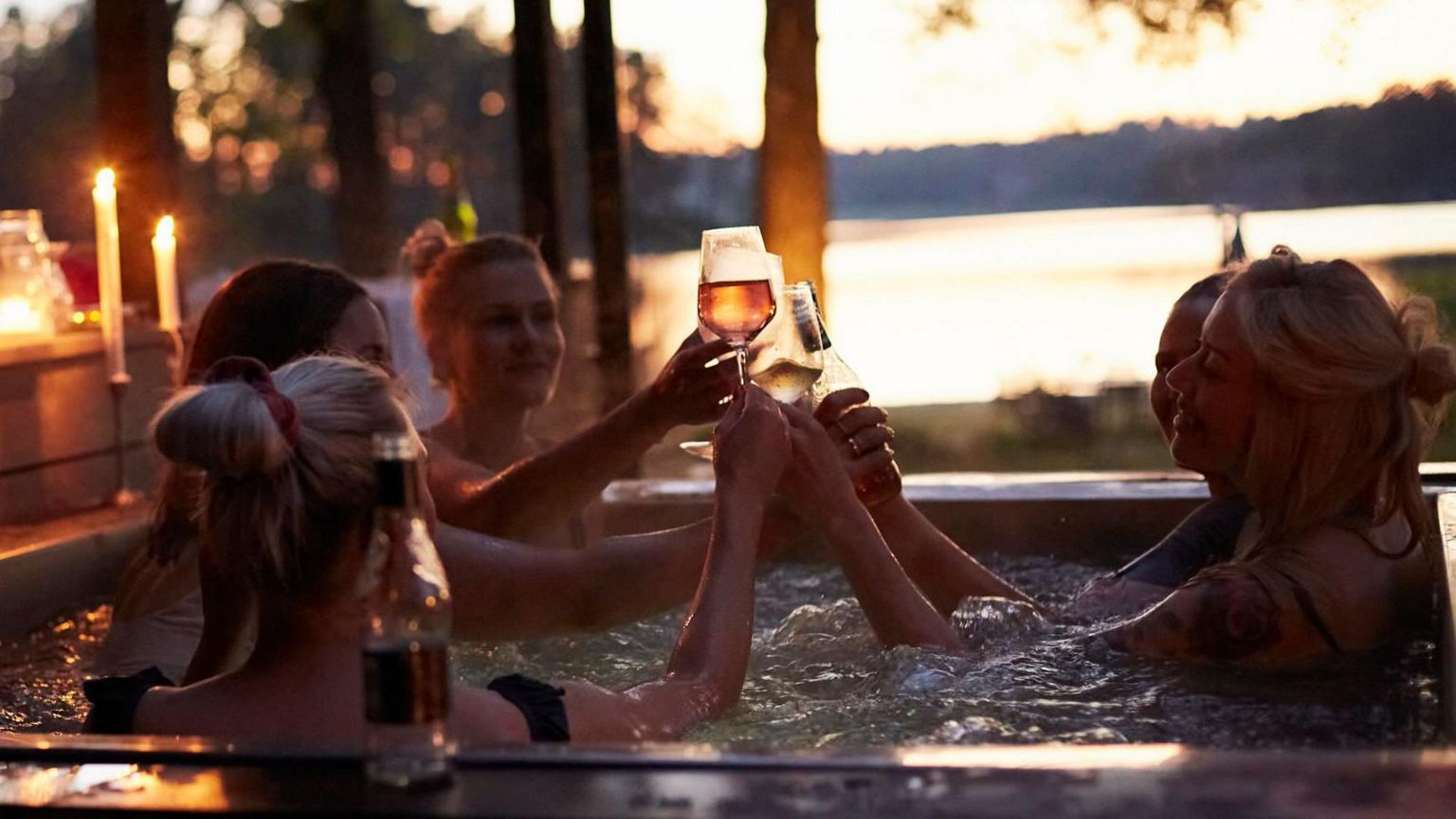 A group of women in a hot tub drinking wine