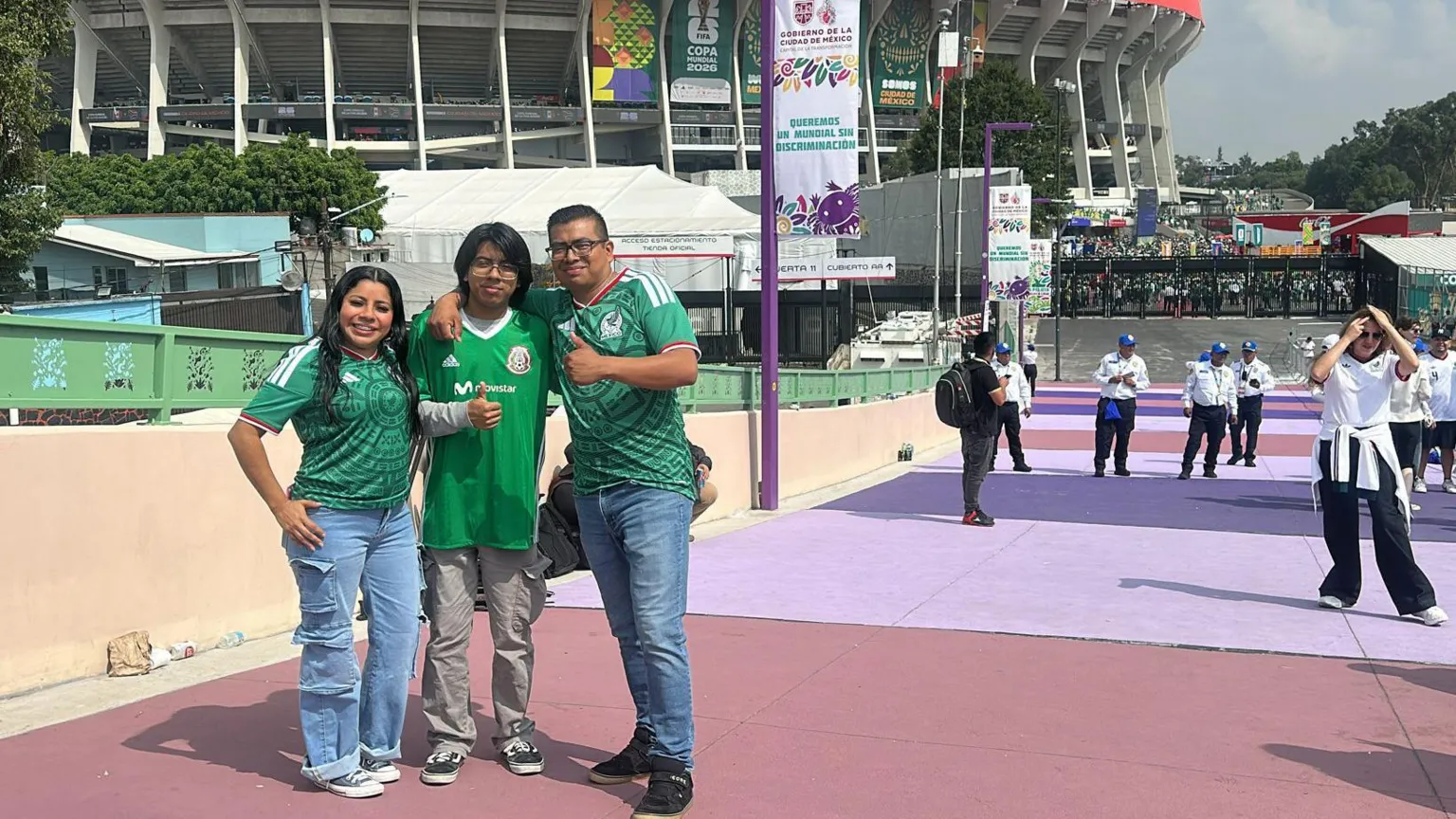 Will Grant / BBC Javier Pérez and his family, wearing Mexico jerseys as they stand in front of the Azteca stadium and give the thumbs up to the camera.
