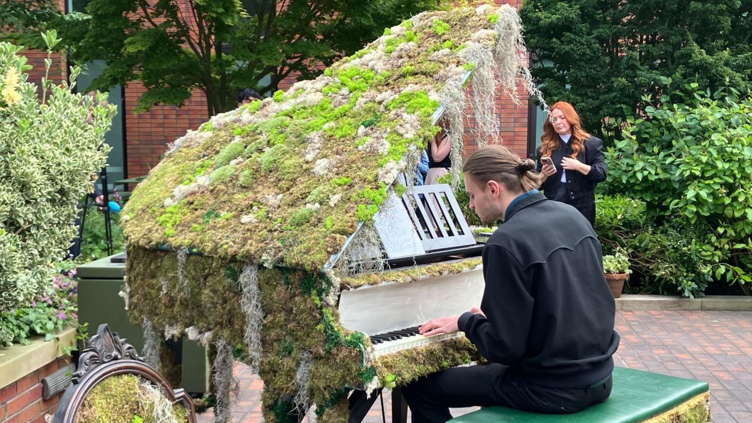 A man playing a piano covered in moss