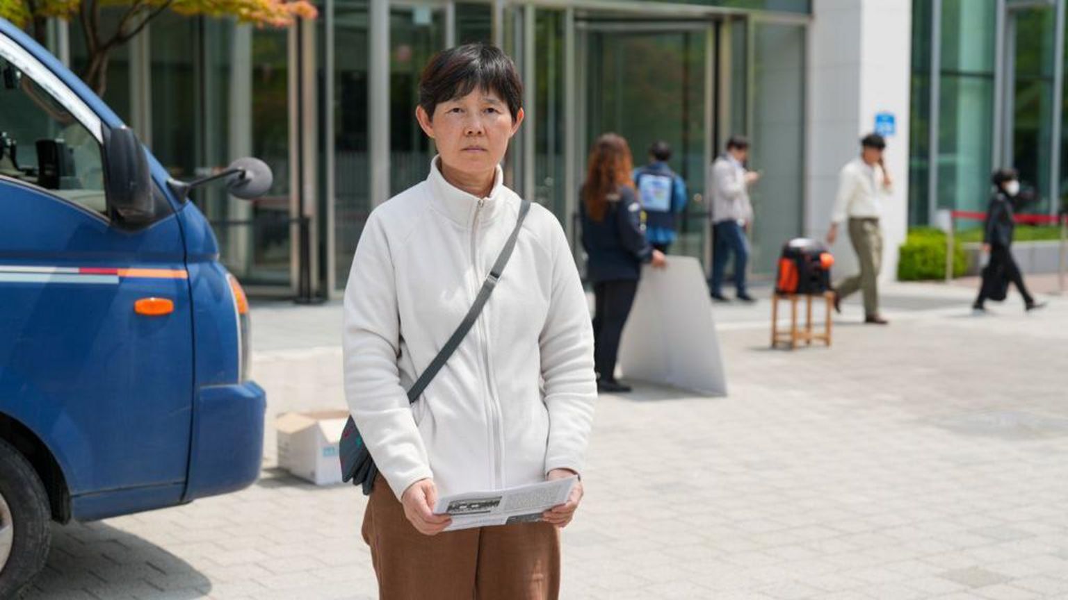 一名身穿白色羊毛短发的中年妇女站在大楼外