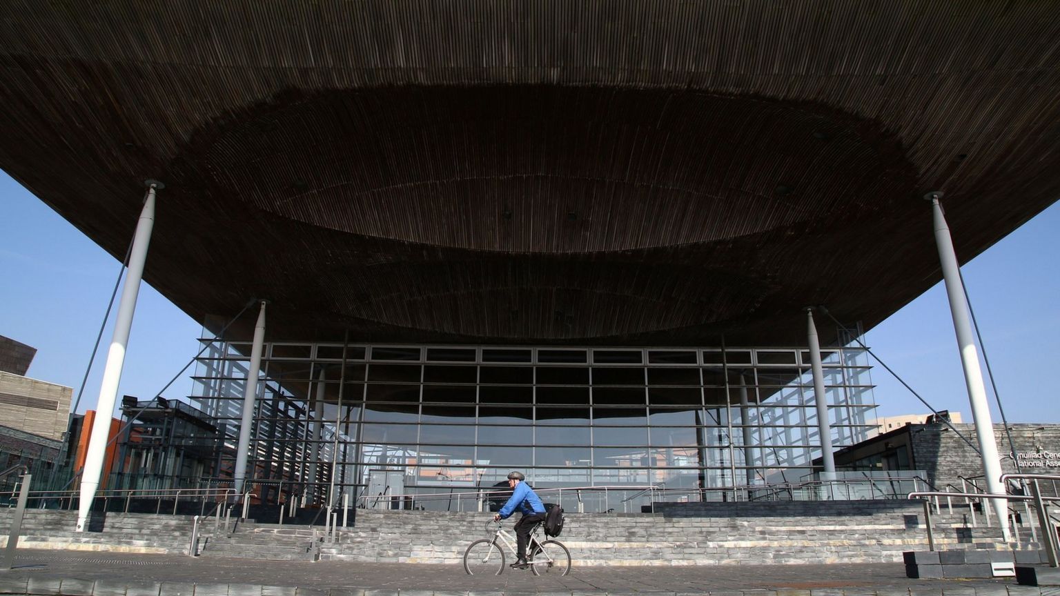 A man riding his bike past the Senedd in Cardiff Bay