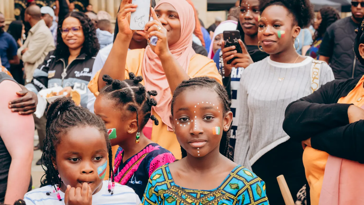 Bradford African Festival of Arts A group of women and children at a festival. Three children can be seen at the front of the crowd, with their faces painted.