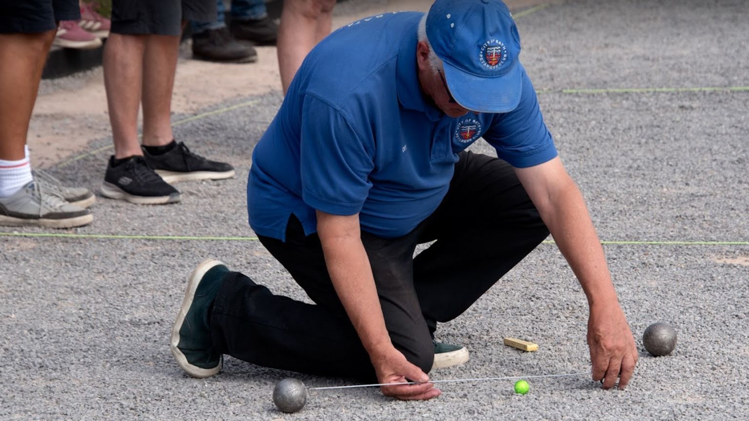 A man measuring the distance between a boule and the jack