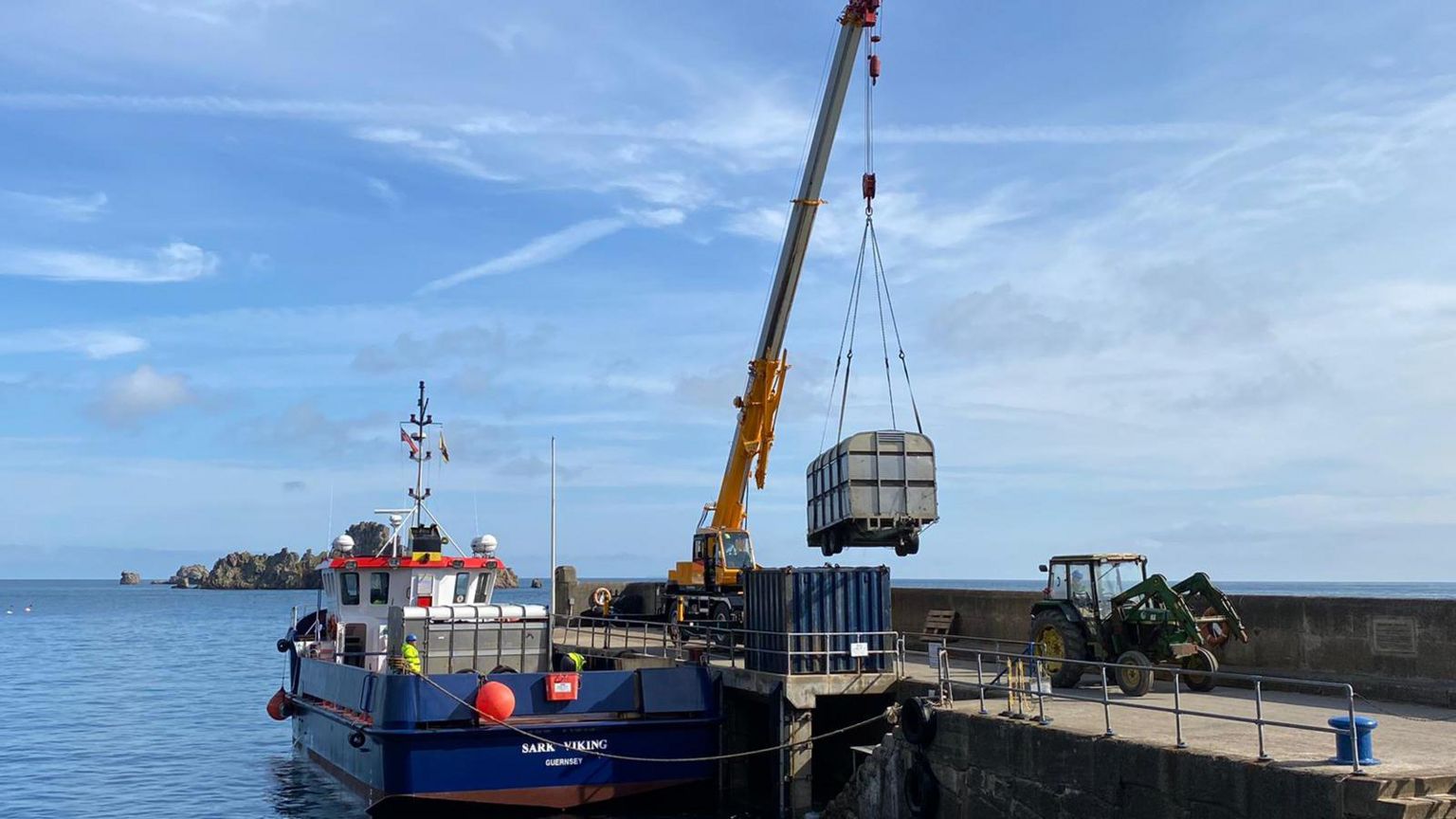 Cows in trailers being lifted off a ferry by crane