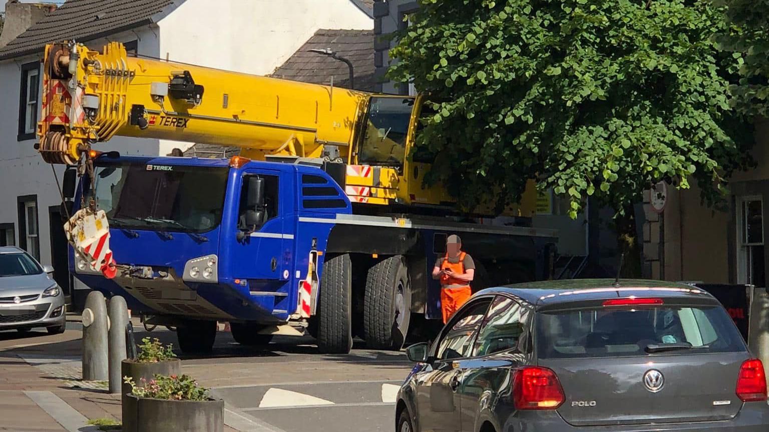 A yellow crane on a blue lorry stuck at the junction