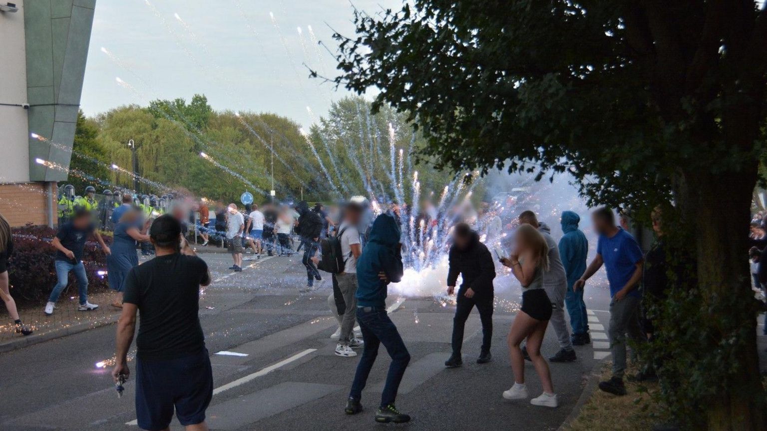 A firework explodes in a street with several people nearby