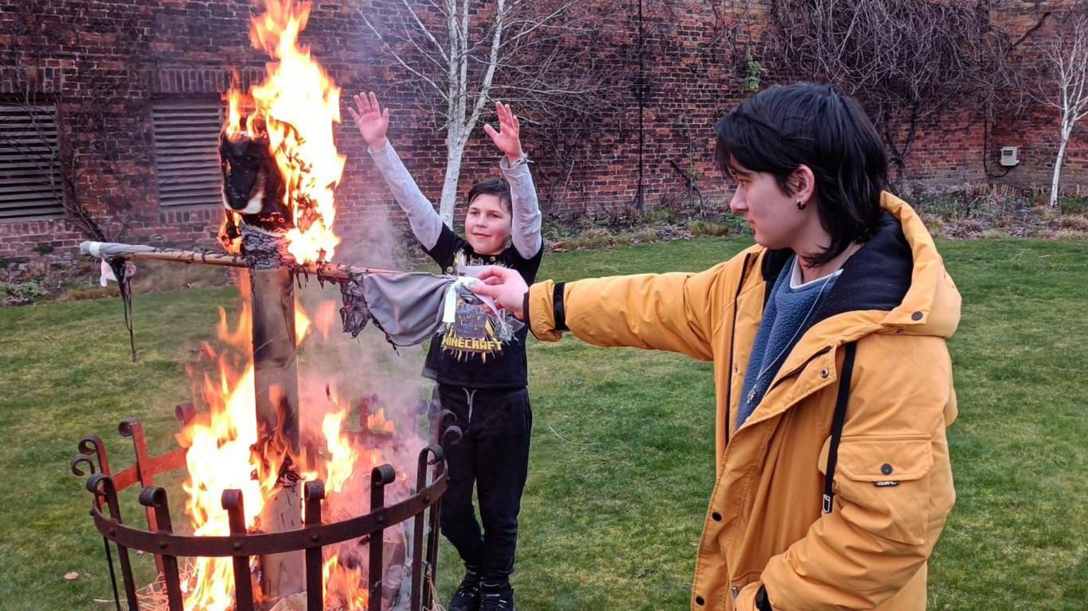 Two young people around a brazier where the figure of a woman called a winter doll  is alight 