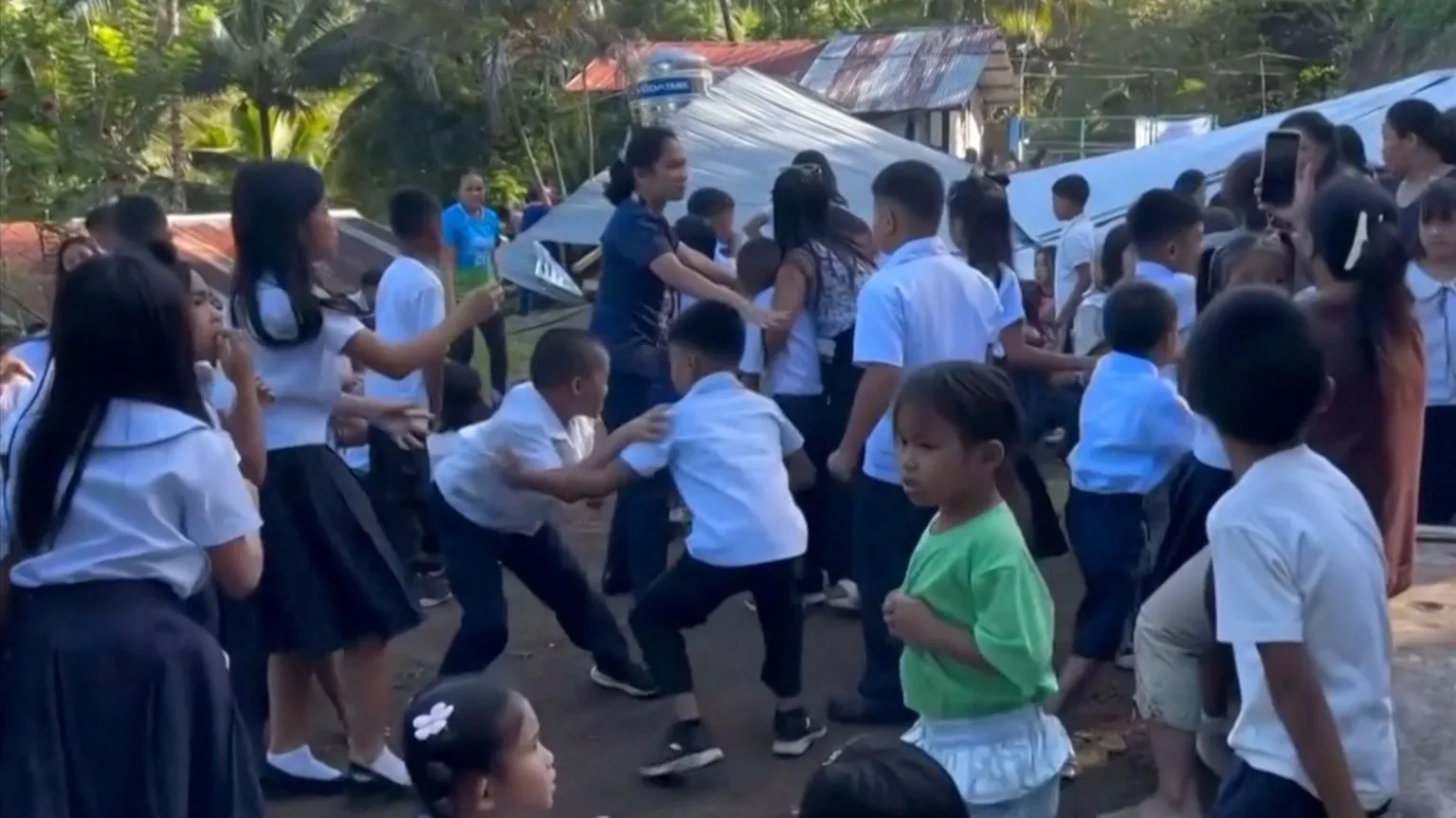Children at a school in the Philippines react after an earthquake strikes, causing an outdoor structure to collapse