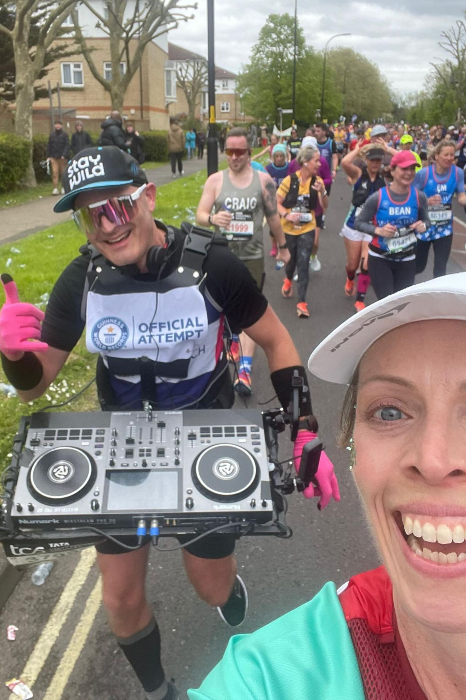 Gus gives a thumbs up to the camera with a pained expression on his face, Emma is taking a selfie of the two of them doing the marathon and she smiles at the camera