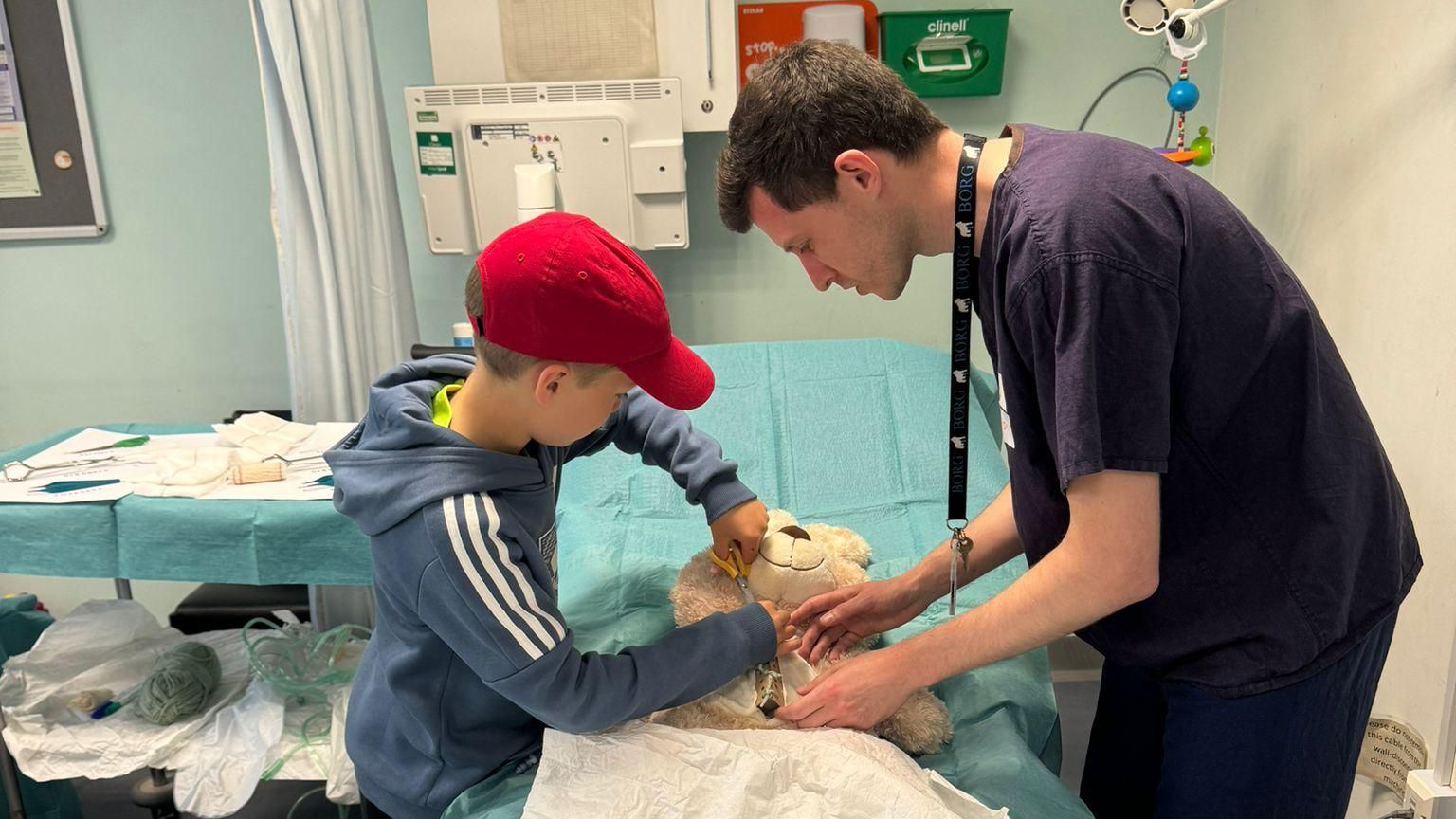 A boy playing hospital with his teddy and a member of staff at RUH