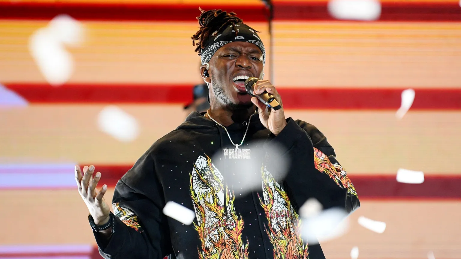 Getty Images KSI is holding a microphone a he performs on stage. He is wearing a black jumper with a print on it.