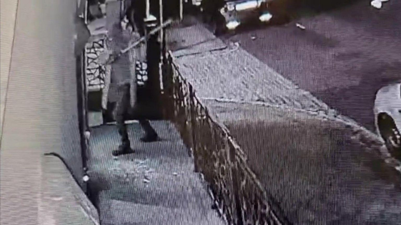 CCTV footage of a man with a metal pole outside Piety mosque. The man is obscured and looks as if he is about to hit the building.