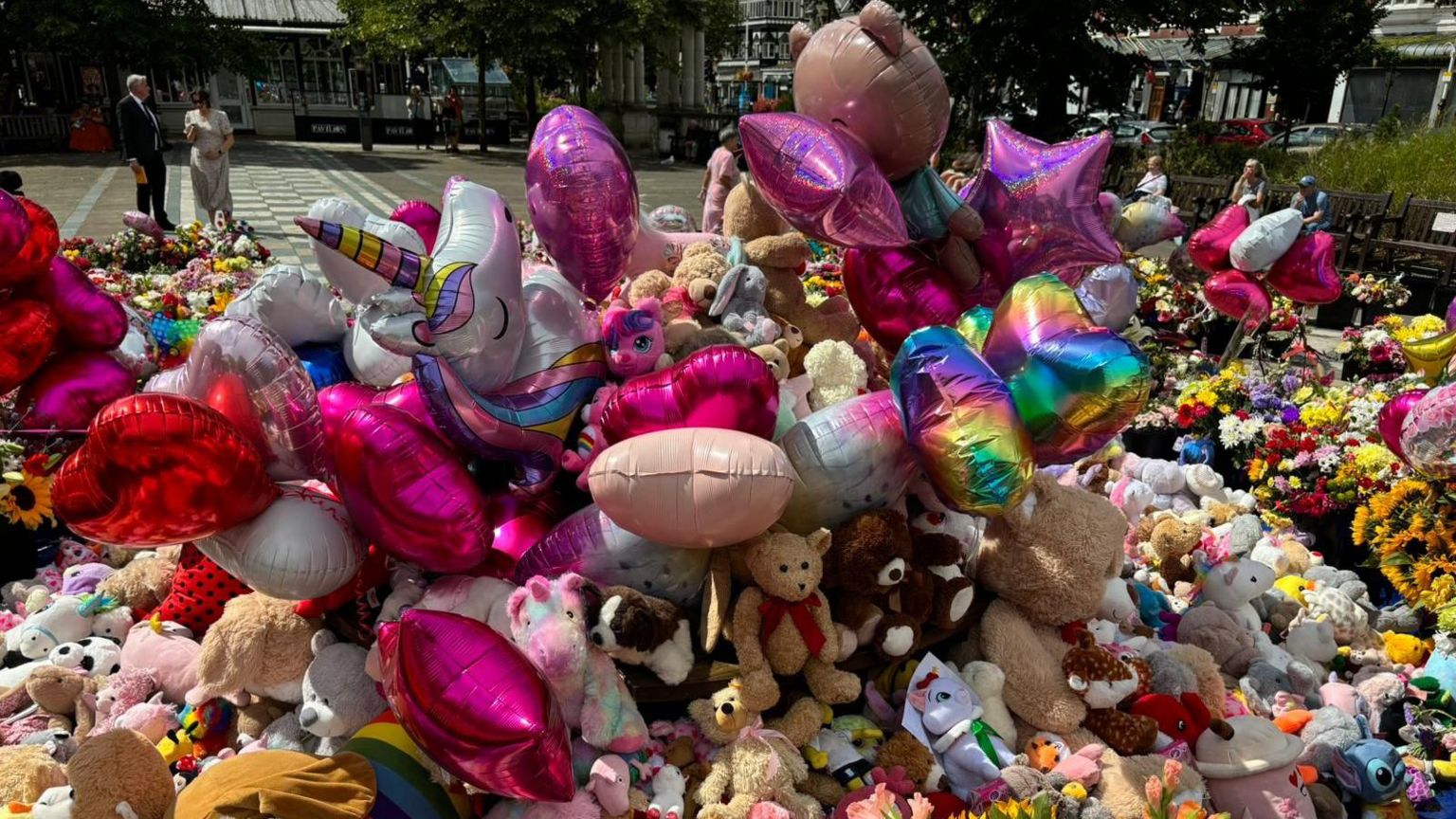 A close up shot of balloons and flowers and teddies