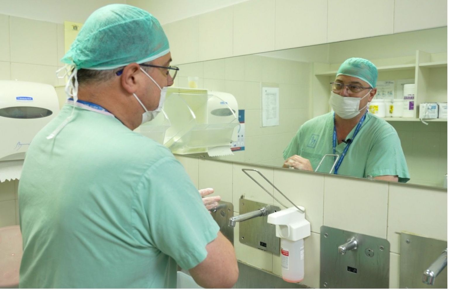 Dr Itai Gat, wearing surgical clothing, washes his hands in preparation for carrying out the procedure to remove sperm