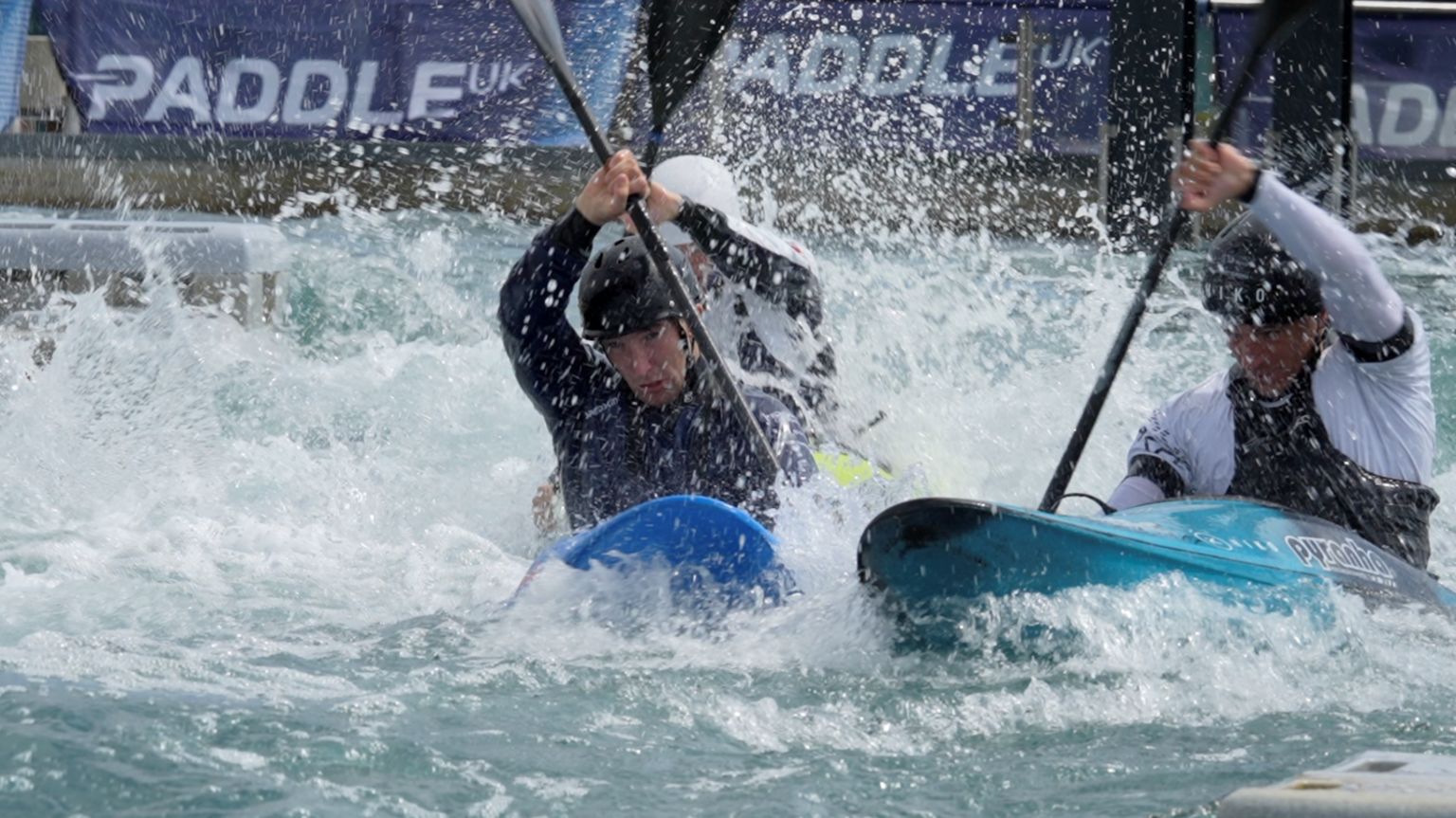 Two kayakers paddling through white water