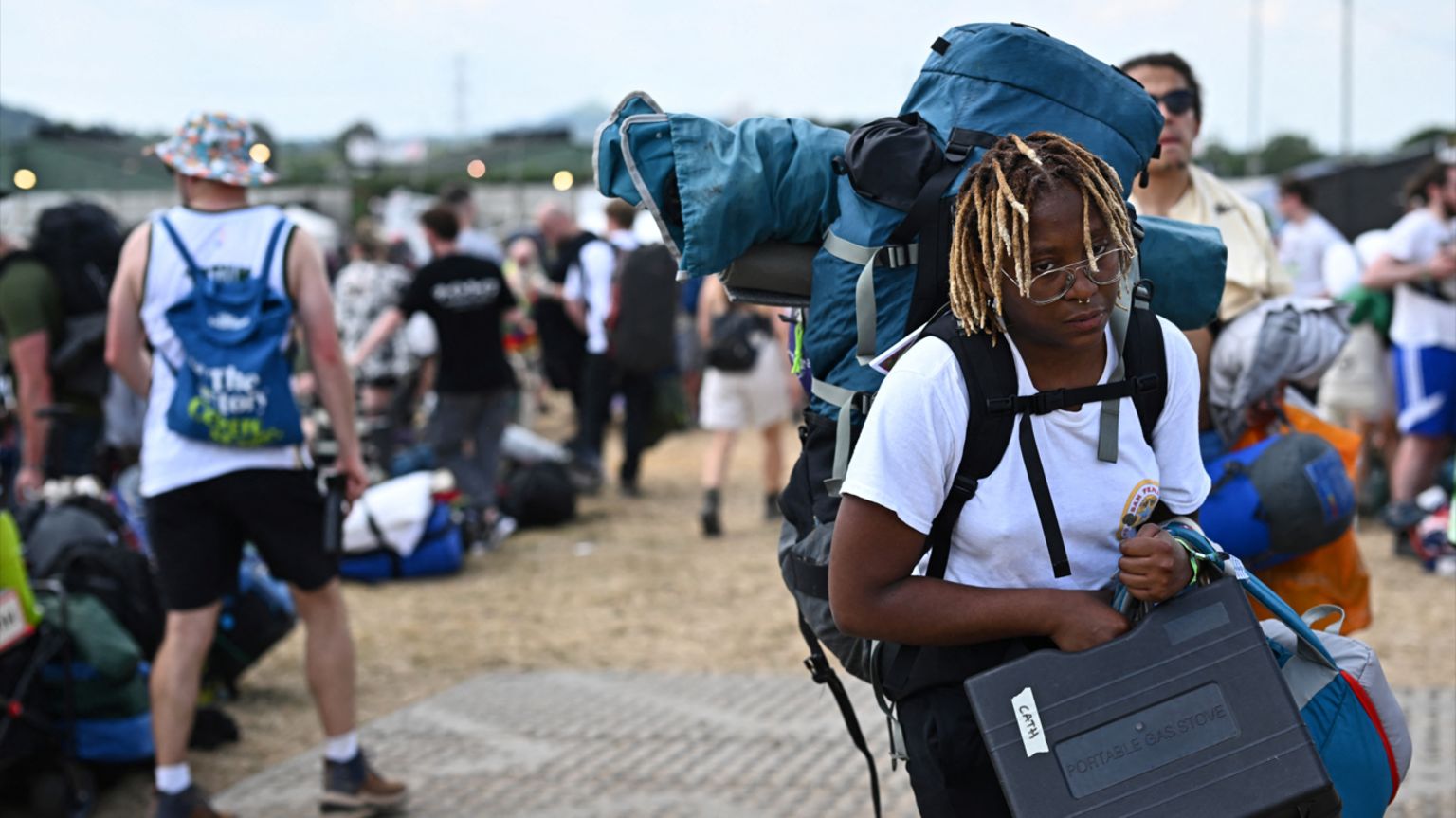 Woman in a white T-shirt arriving at Glastonbury carrying bags