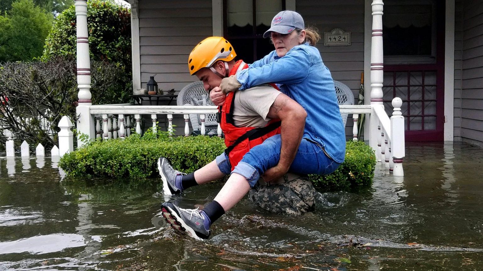 A woman is carried through flood waters on a man's back in Houston