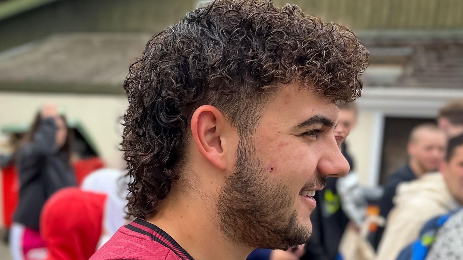 Man in a crowd with a dark mullet 