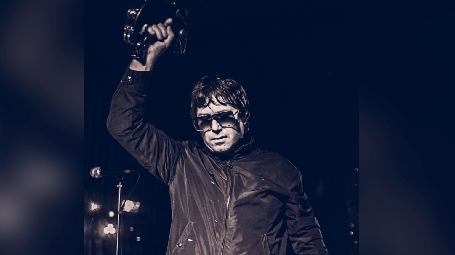 Kelvin Brierley performing on stage and holding a tambourine above his head