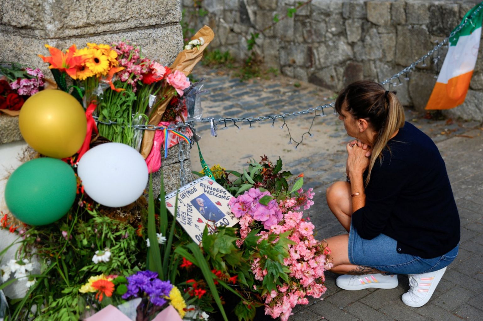 A woman kneels near tributes outside late Irish singer Sinead O'Connor's former home