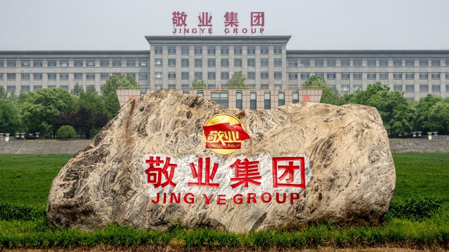 河北石家庄平山县中国敬业集团总部办公楼前花园内，摆放着一座带有企业标志的石雕（9/3/2020）