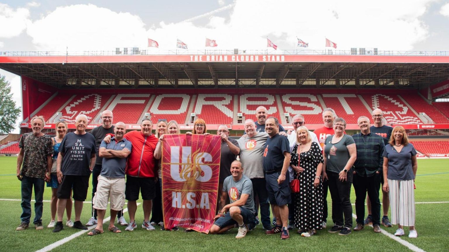 Supporters stand on the pitch with a banner